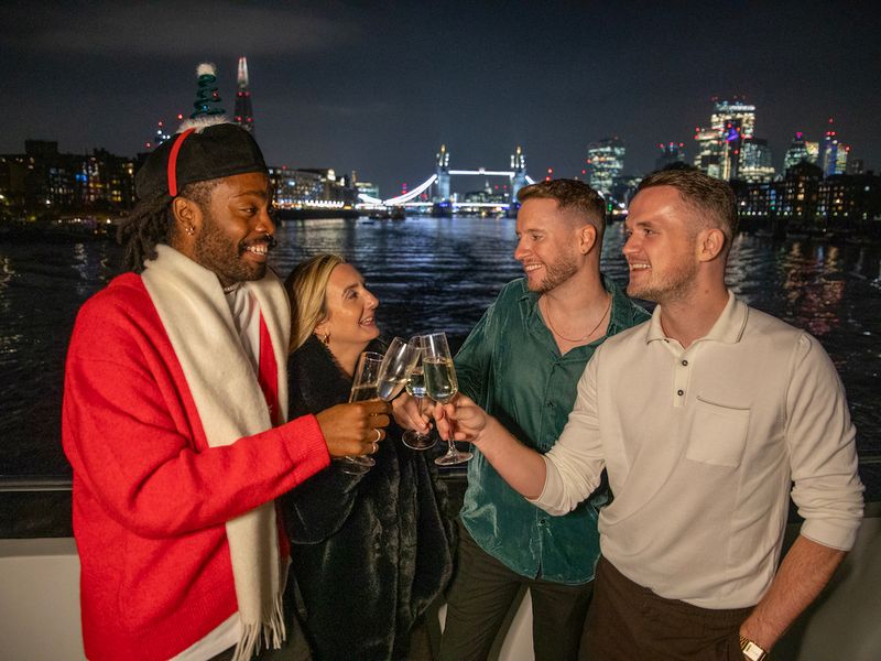 Gäste stoßen bei einer weihnachtlichen Dinner Cruise auf der Themse mit Blick auf die Tower Bridge an