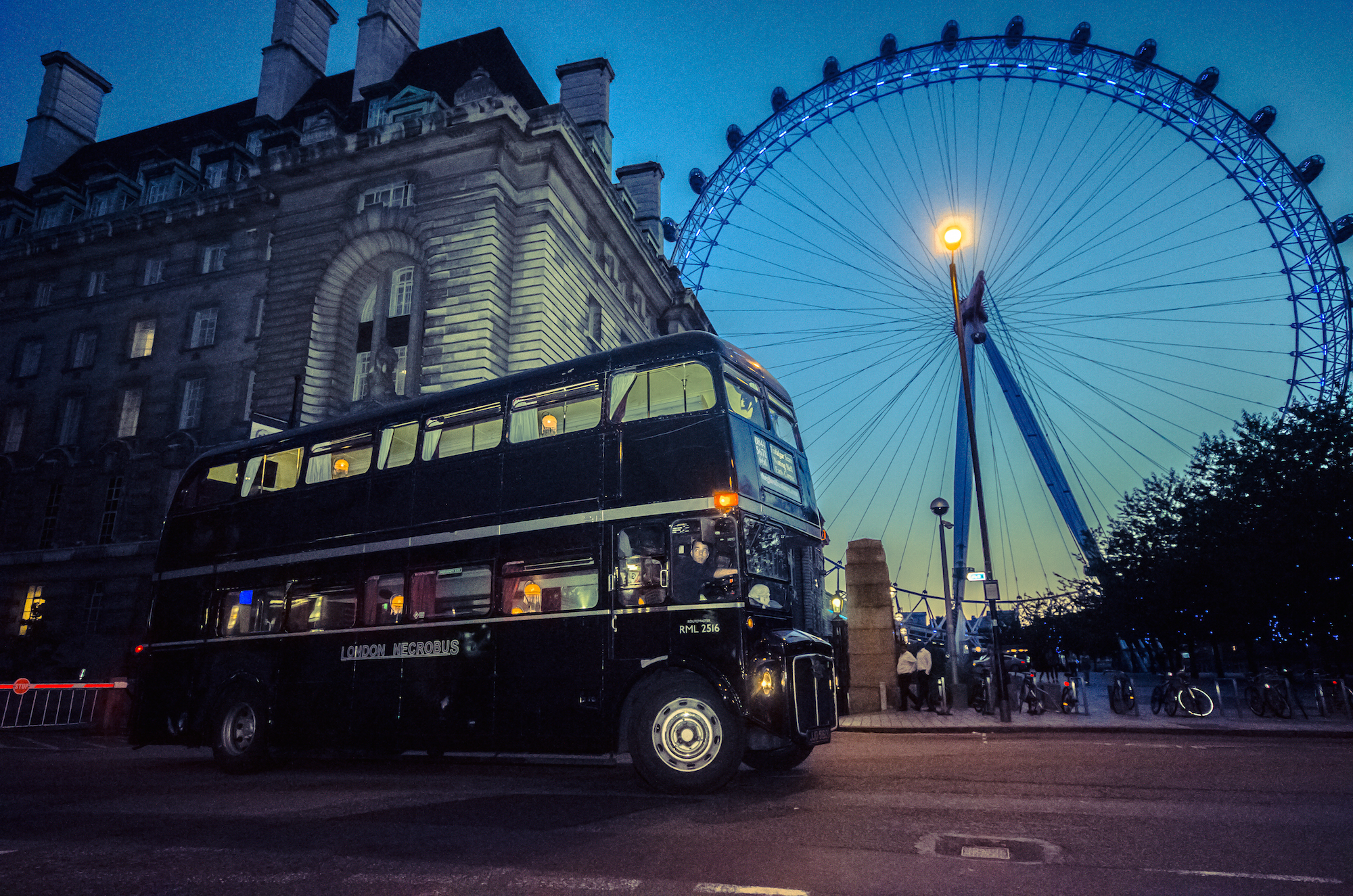 Schwarzer London Necrobus mit beleuchtetem London Eye im Hintergrund