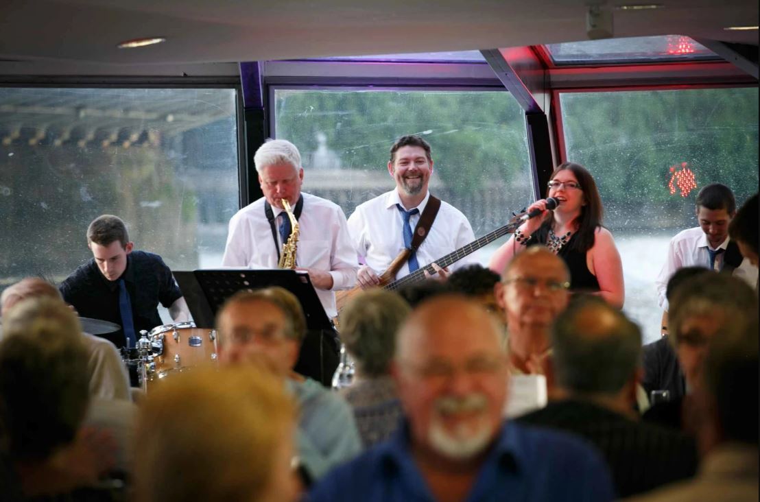 Frontalansicht Band spielt auf Bühne auf Fähre mit verschwommenen Publikum davor in London