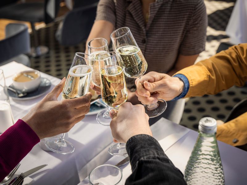 Gäste stoßen mit Sekt während einer Lunch Cruise auf der Themse in London an