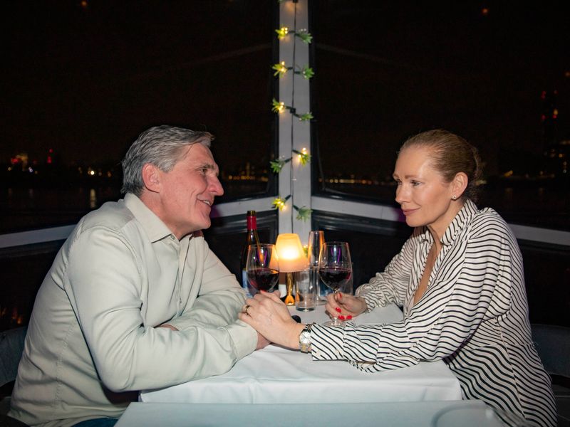 Paar genießt Wein und Dessert bei einem romantischen Dinner an Bord eines Schiffes auf der Themse