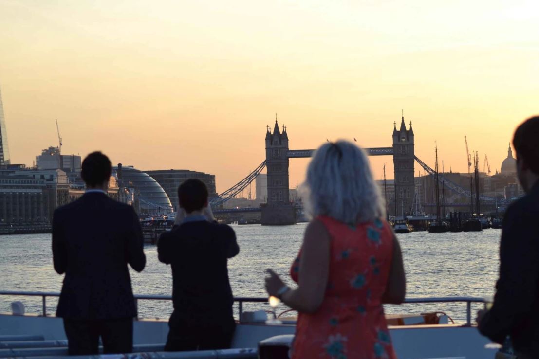 Vier Personen auf Fähre die Sonnenuntergang fotografieren in London