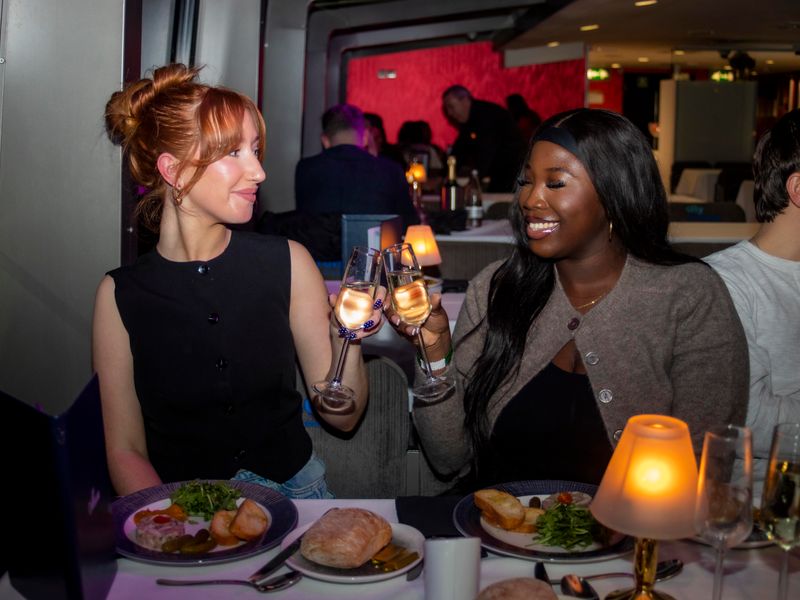 Zwei Gäste stoßen bei einem Abendessen mit Sekt während einer Dinner Cruise in London an