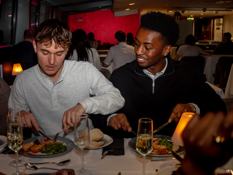 Gäste genießen ein mehrgängiges Abendessen und Sekt an Bord einer Dinner Cruise auf der Themse