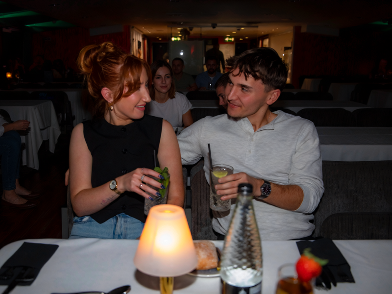 Zwei Gäste genießen Drinks bei stimmungsvoller Beleuchtung während einer Dinner Cruise auf der Themse