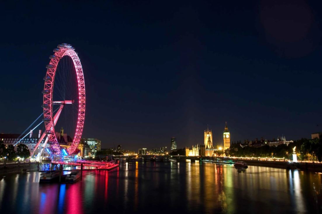 Nachtaufnahme Skyline mit London Eye leuchtend rot und Parlament mit Big Ben im Hintergrund