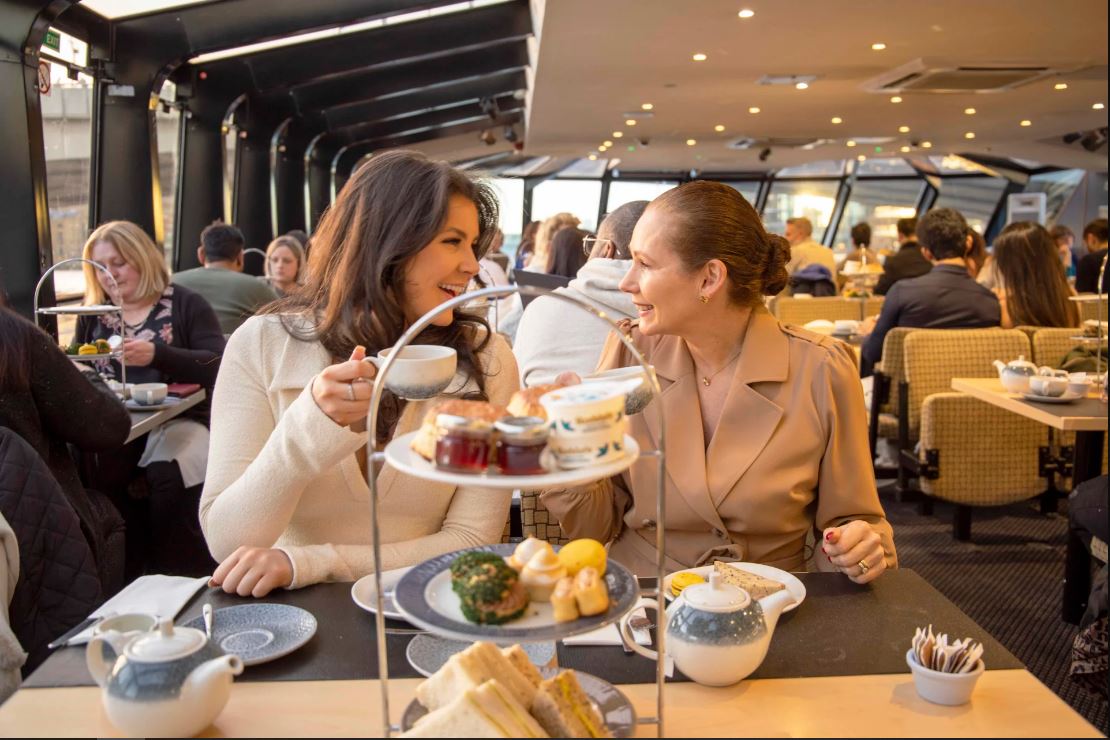 Frauen mit Tee in der Hand gucken sich lächelnd an in London