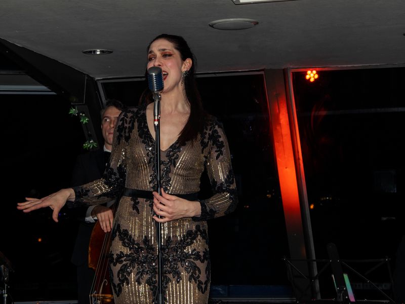 Sängerin sorgt mit Live-Musik für Unterhaltung während einer abendlichen Dinner Cruise auf der Themse