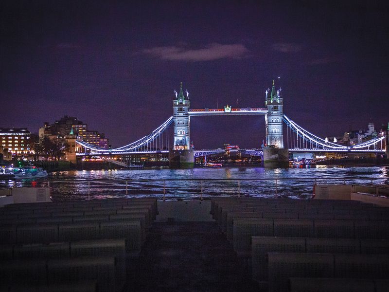 Beleuchtete Tower Bridge bei Nacht vom Schiff auf der Themse in London gesehen